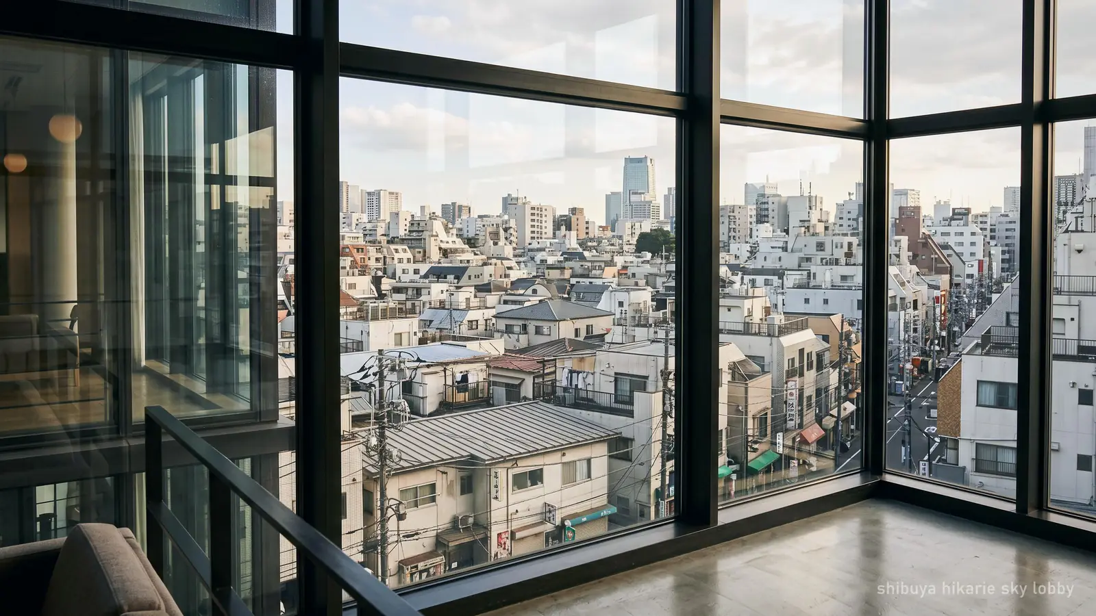Shibuya's low-rise rooftops seen through a building window in afternoon light