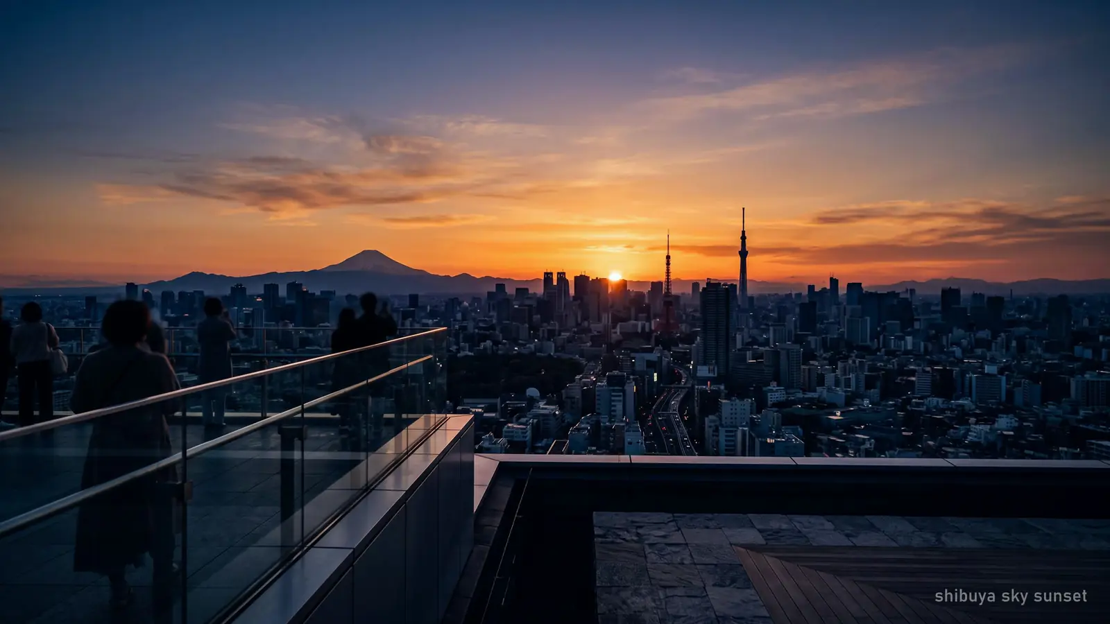 Golden hour from the rooftop, the sky banded orange into deep blue behind silhouetted towers